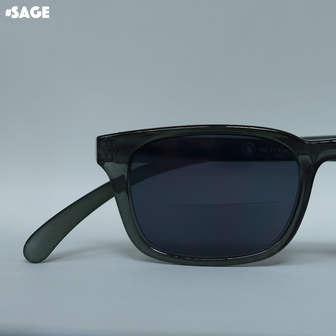 Eine Salbei farbene transparente Sonnenbrille auf grauem Hintergrund.