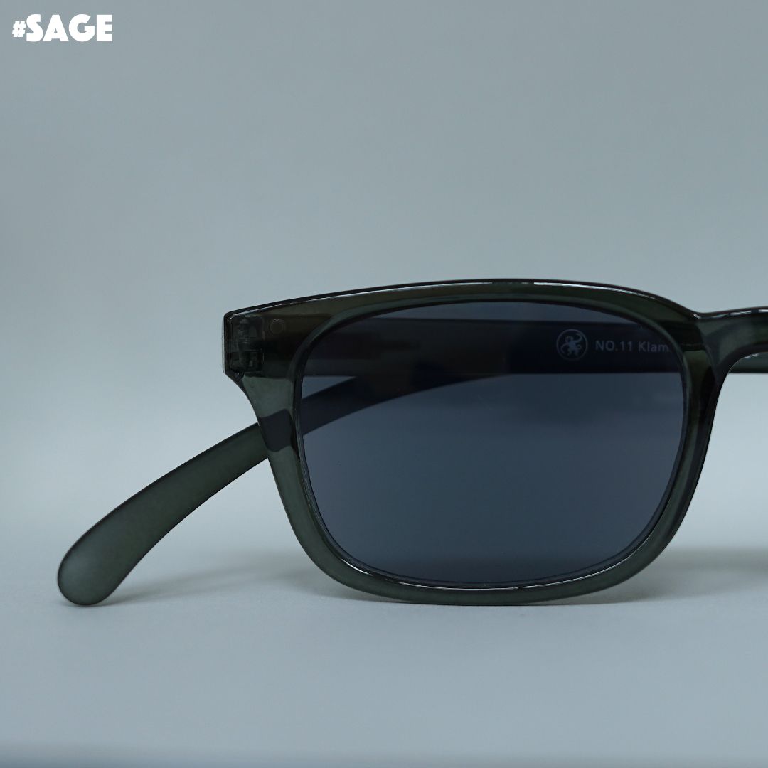 Salbei-farbene transparente Brille auf grauem Hintergrund.