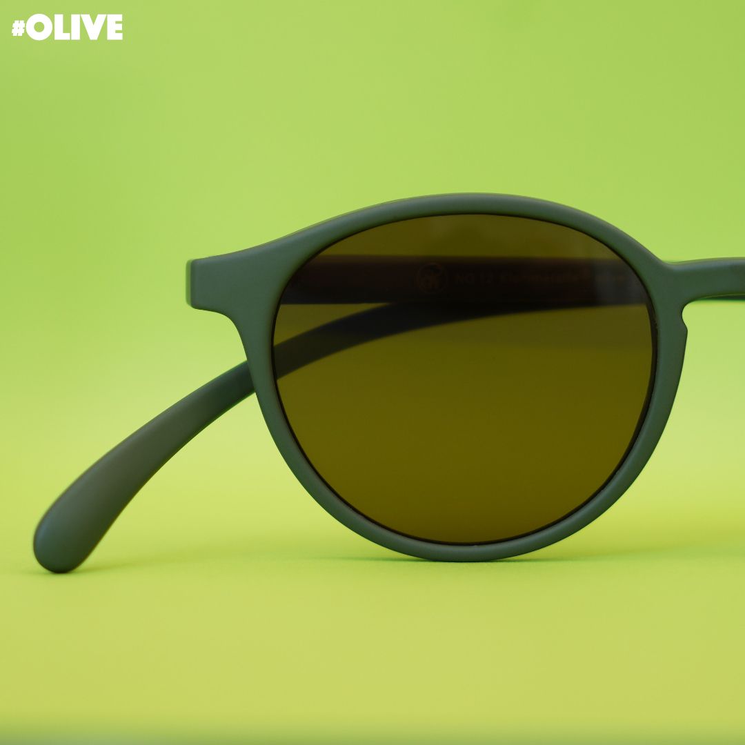 Eine olive farbene Sonnenbrille auf grünem Hintergrund.