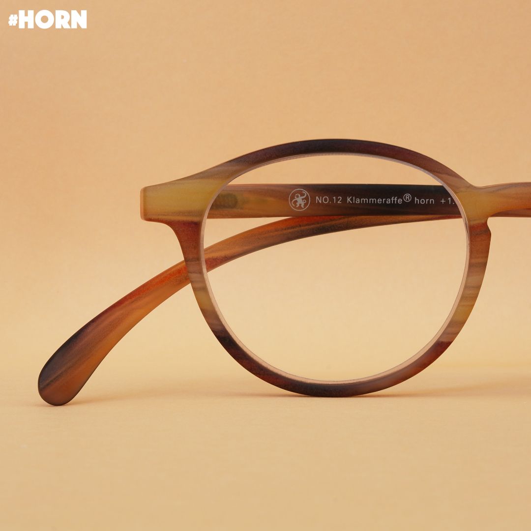 Eine horn farbene Brille auf braunem Hintergrund.