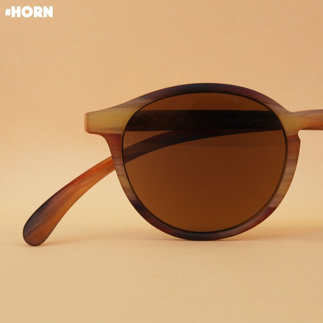 Eine horn farbene Sonnenbrille auf braunem Hintergrund.