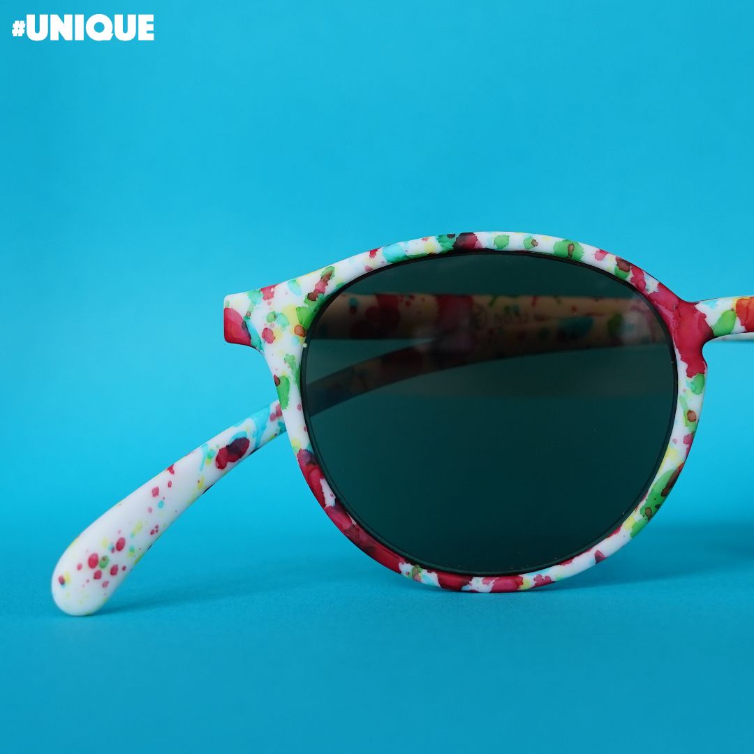 Bunte, mit Farbspritzern bemalte Sonnenbrillen vor hellblauem Hintergrund.