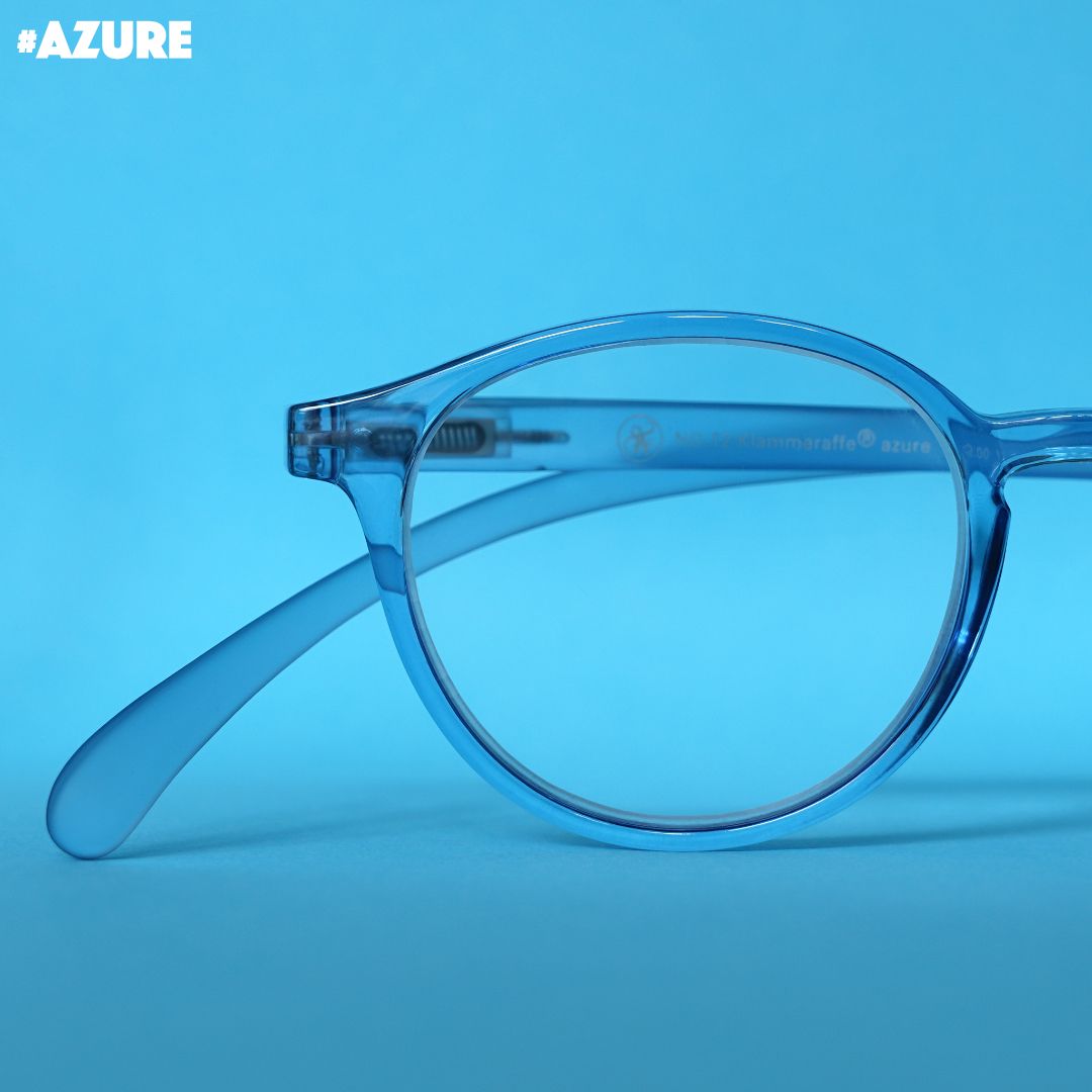 Eine azure farbene transparente Brille auf blauem Hintergrund.