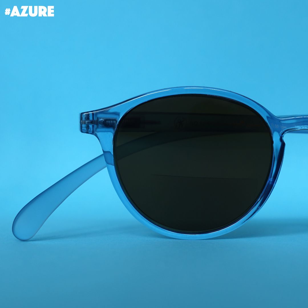 Eine azure farbene transparente Bifokal-Sonnenbrille auf blauem Hintergrund.