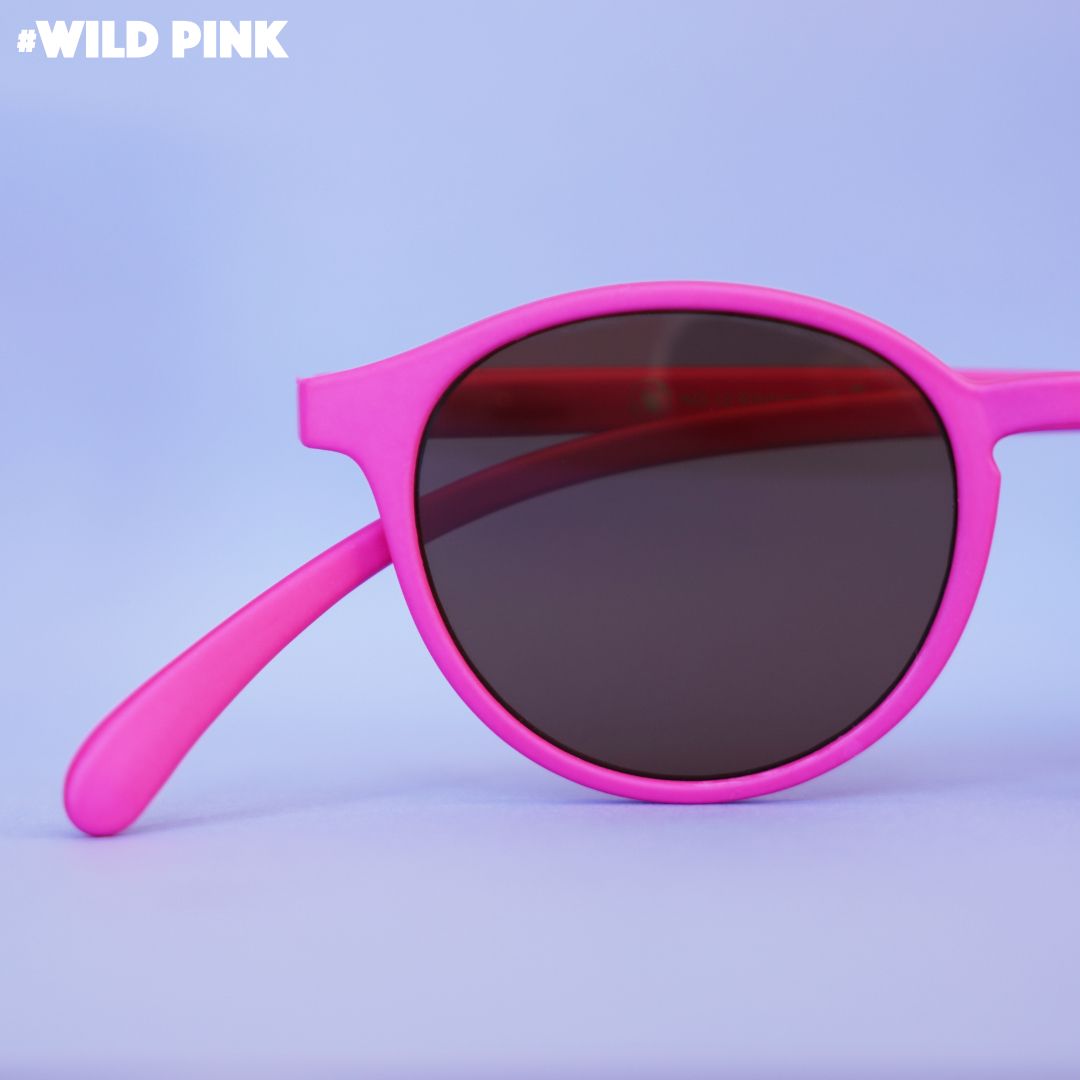 Eine rosa farbene Lesebrille auf Flieder farbenem Hintergrund.