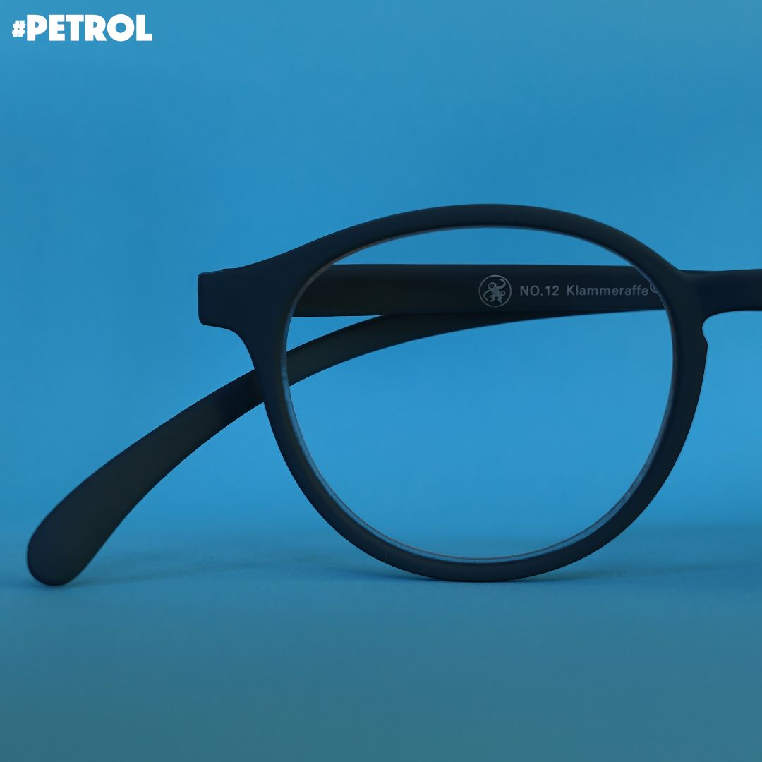 Eine petrol farbene Brille auf blauem Hintergrund.