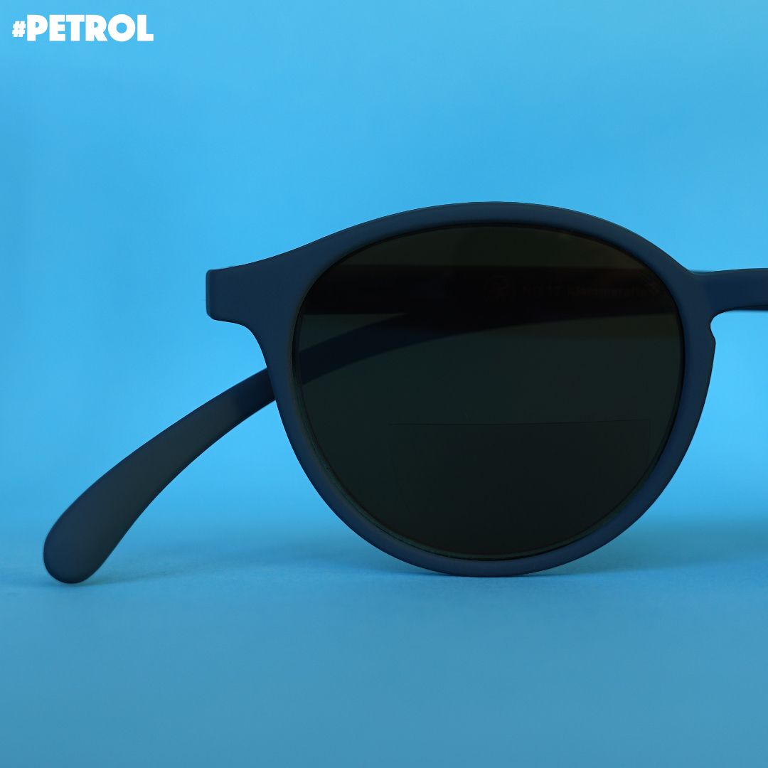 Eine petrol farbene Bifokal-Sonnenbrille auf blauem Hintergrund.