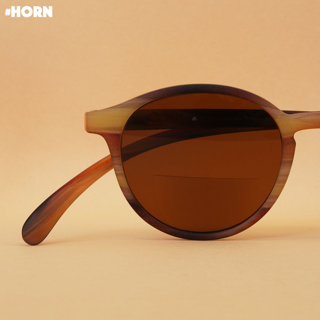 Eine horn farbene Bifokal-Sonnenbrille auf braunem Hintergrund.