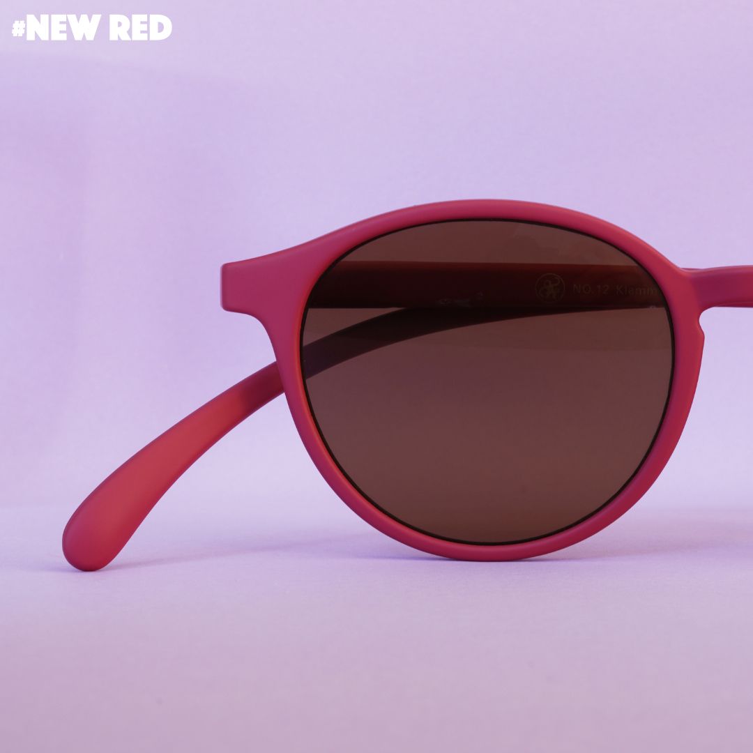 Eine rote Lesebrille auf rosa farbenem Hintergrund.