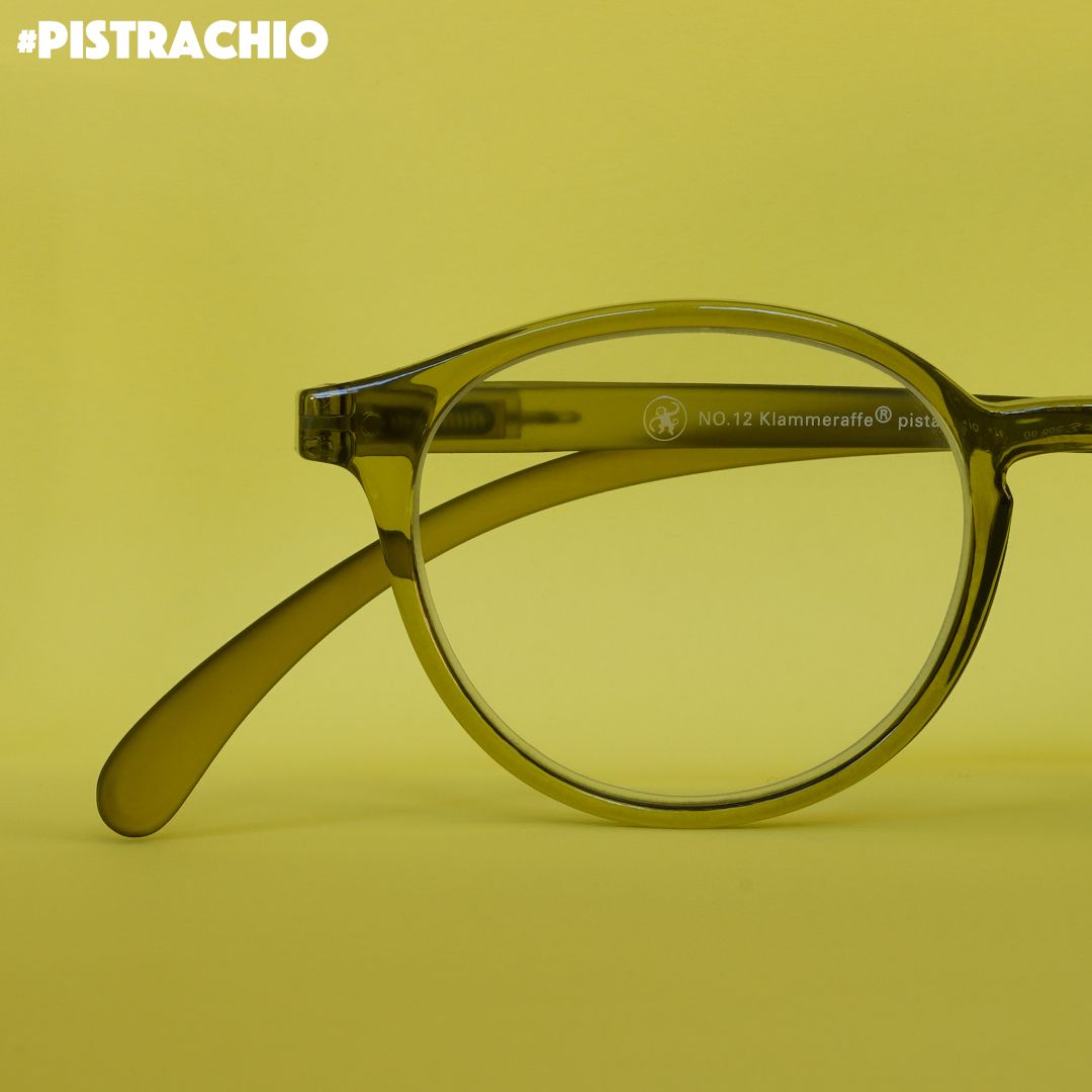 Eine Pistazien farbene transparente  Brille auf grünem Hintergrund.