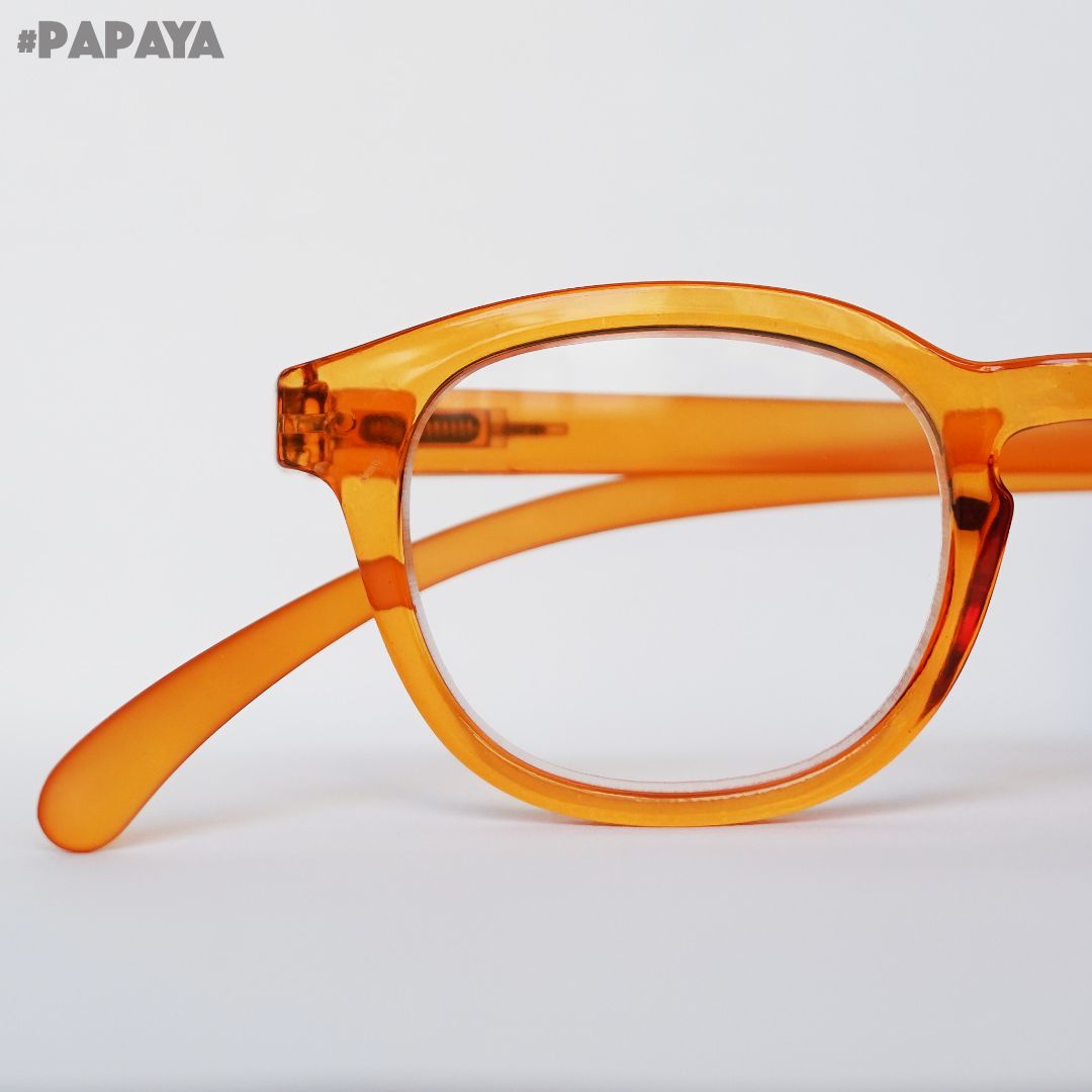Papaya farbene Brille auf grauem Hintergrund.