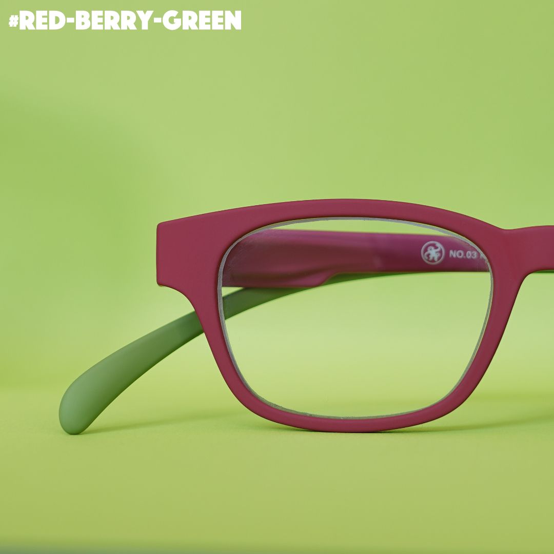 Eine rot-grüne farbene Lesebrille auf grünem Hintergrund.