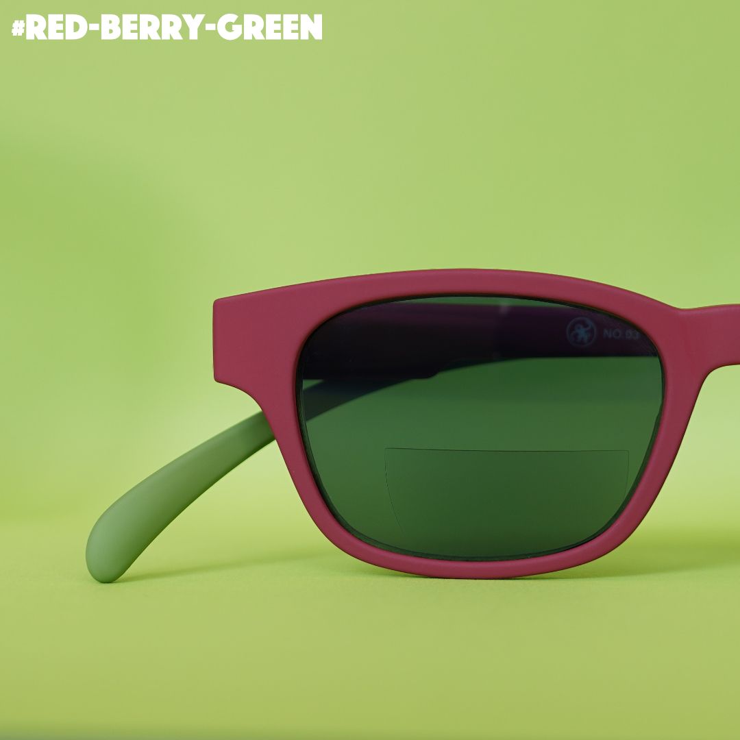 Eine rot-grün farbene Bifo-Sonnenbrille auf grünem Hintergrund.