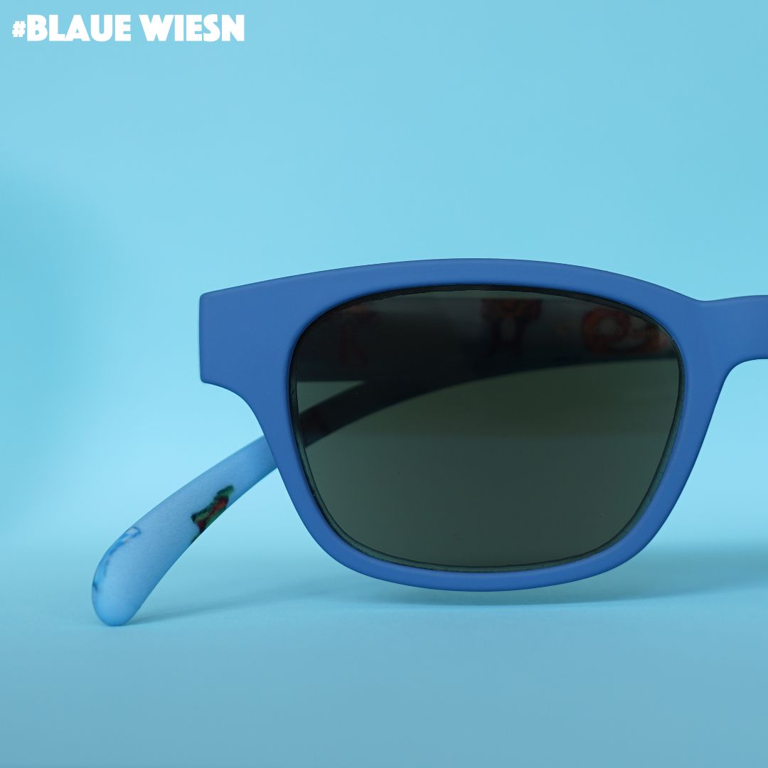 Eine blaue Sonnenbrille mit blauen Bügeln im Wiesn Look auf blauem Hintergrund.