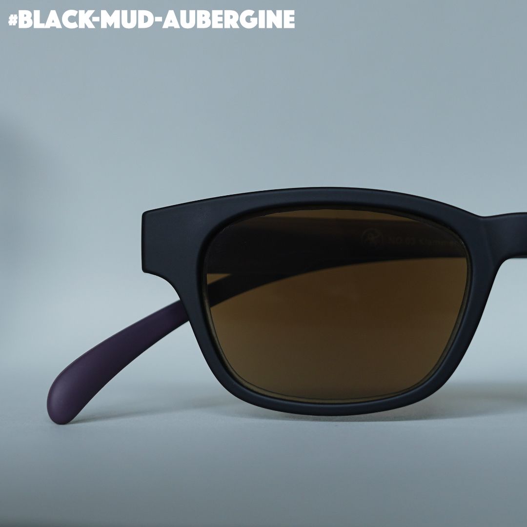 Eine schwarz-aubergine farbene Sonnenbrille auf grauem Hintergrund.