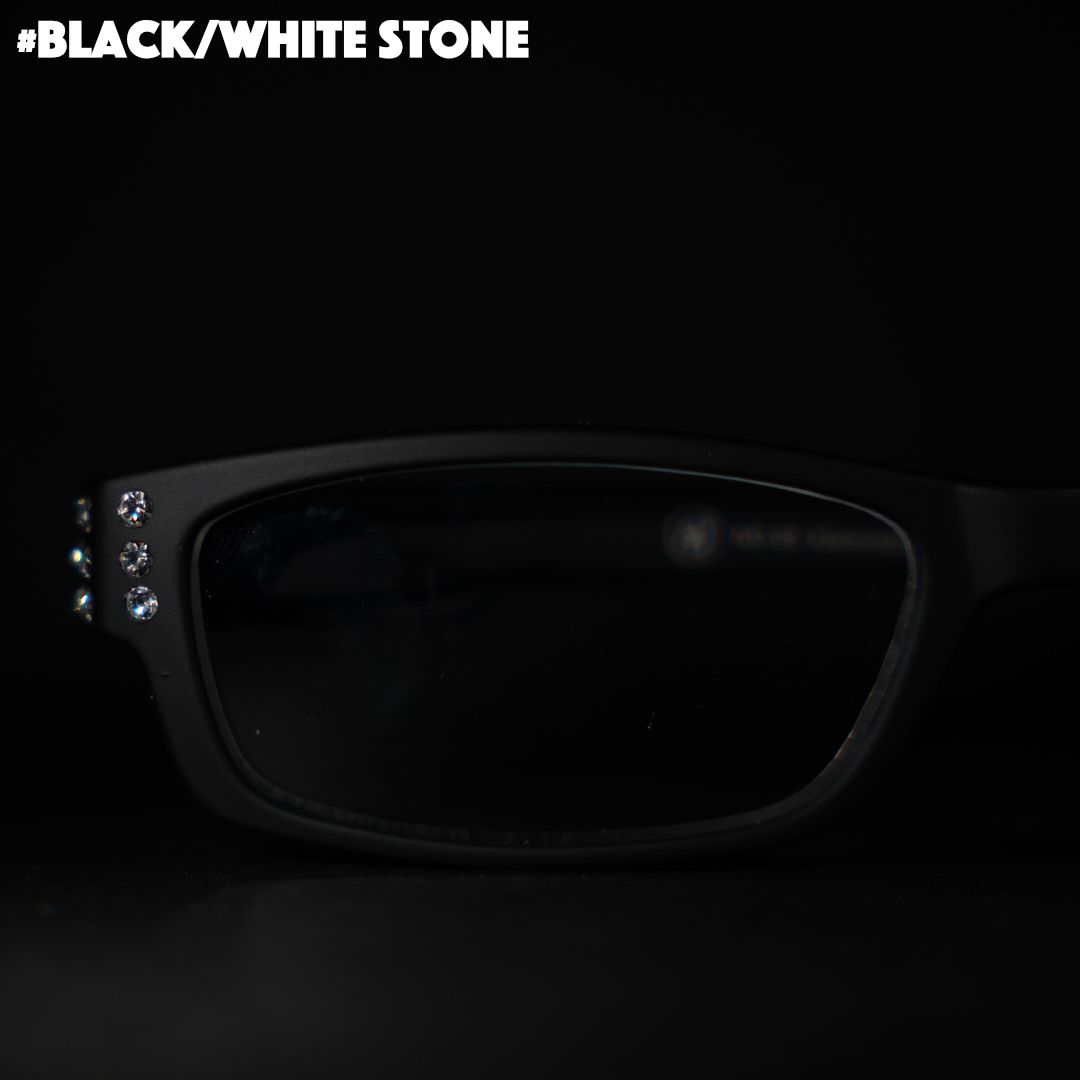 Eine schwarze Lesebrille mit Strasssteinen auf schwarzem Hintergrund.