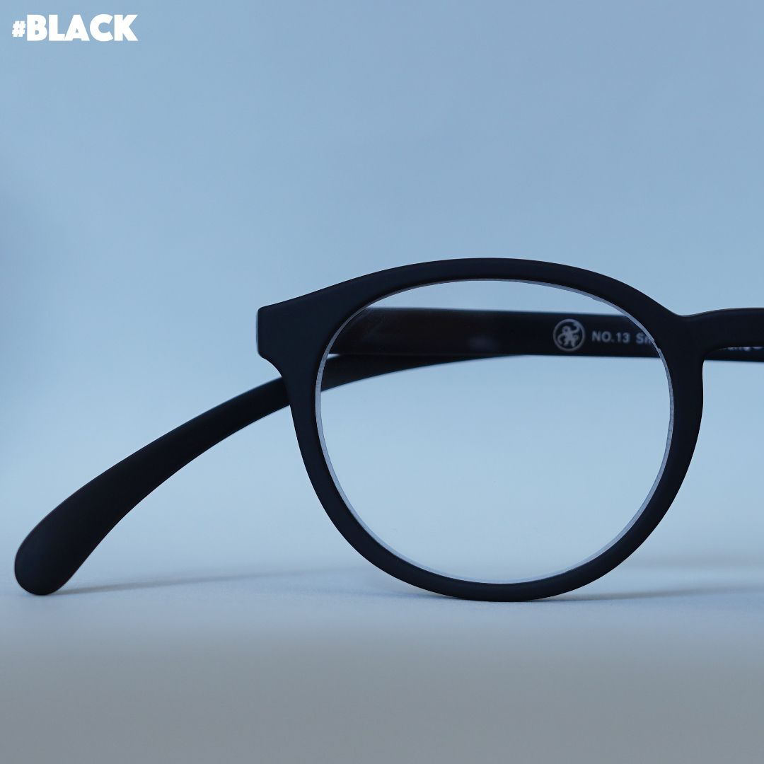 Eine schwarze Panto-Brille auf grauem Hintergrund.