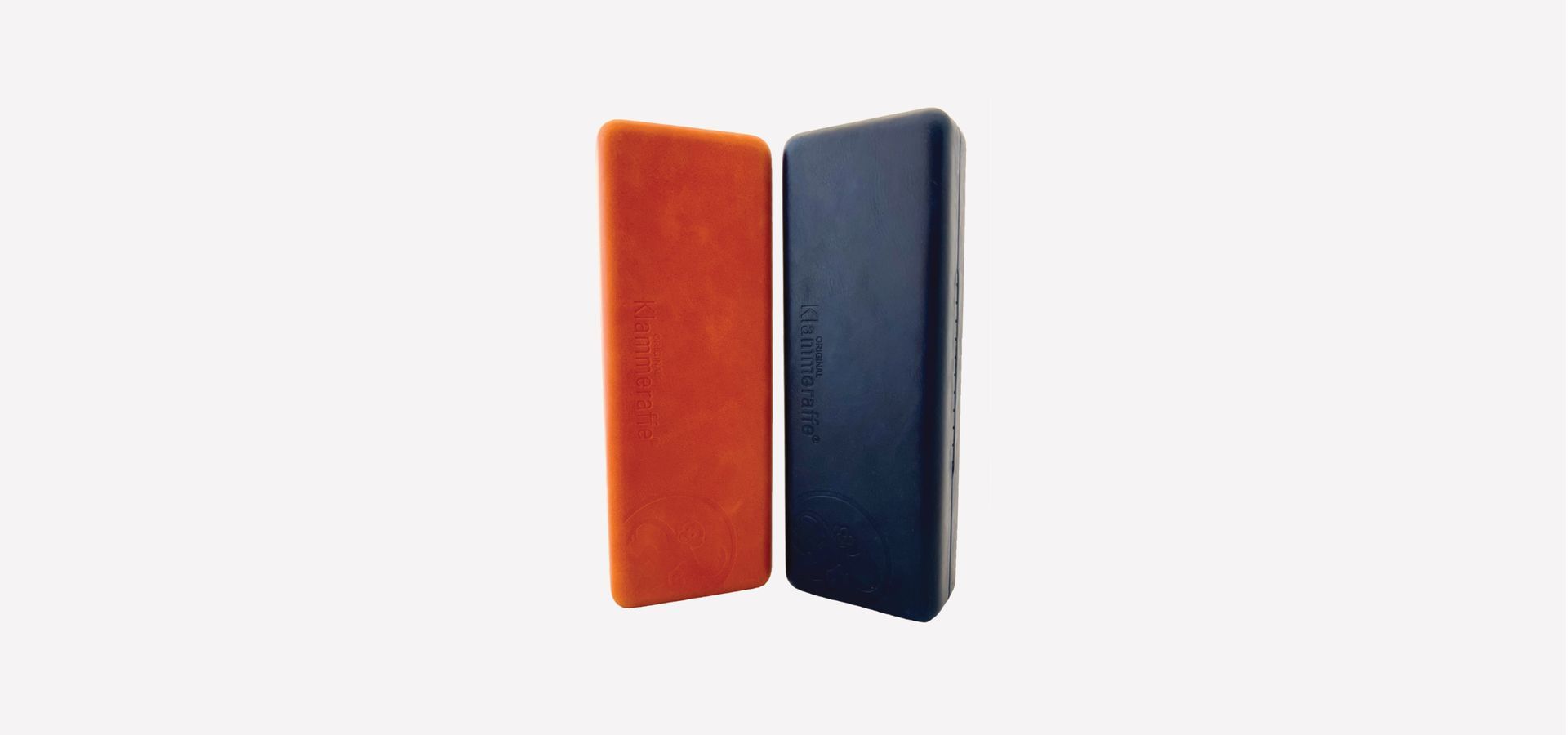 Zwei Brillenetuis, eine in der Farbe Cognac und ein in Dunkelblau. Beides auf weißem Hintergrund.