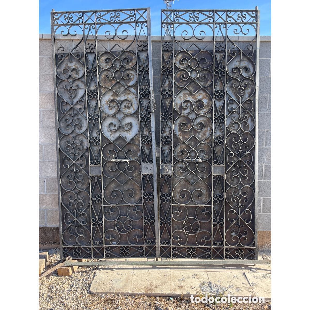 Una puerta de hierro forjado se encuentra frente a una pared de ladrillos.