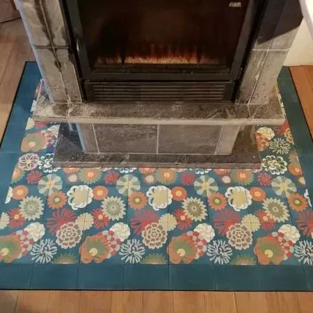 Ein Kamin mit einem gefliesten Schutzbereich davor.