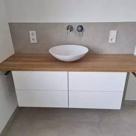 Ein Badezimmerwaschtisch mit Waschbecken und Holzarbeitsplatte.