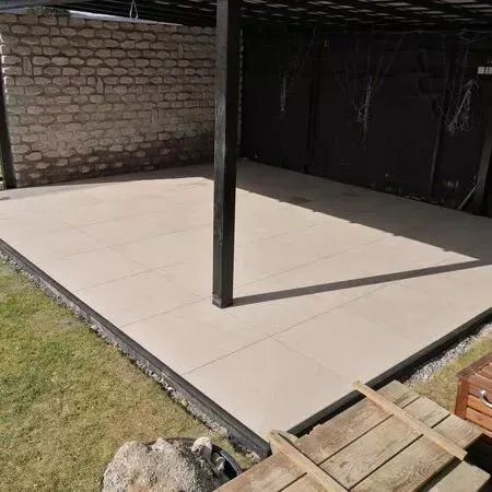 Eine Terrasse mit einer Pergola und einer Backsteinmauer im Hintergrund.