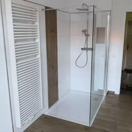 Ein Badezimmer mit ebenerdiger Dusche und Handtuchhalter.