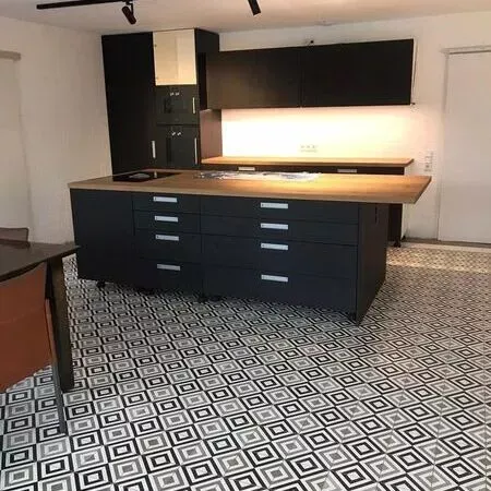 Eine Küche mit schwarzen Schränken und einem schwarz-weißen Fliesenboden.