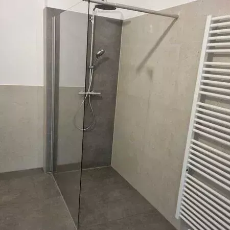 Ein Badezimmer mit ebenerdiger Dusche und Handtuchhalter.