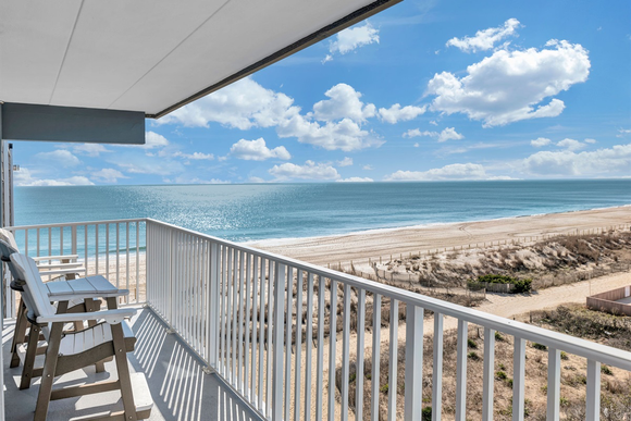 A porch with a couch and chairs and a view of the water.