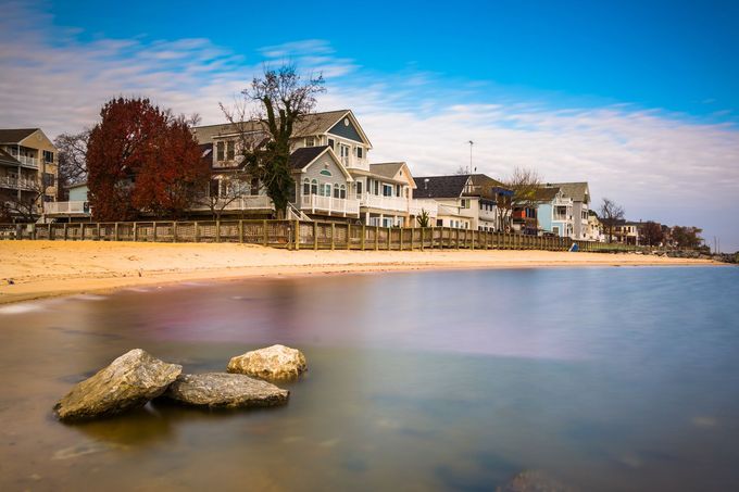 A long exposure photo of a beach with houses in the background.