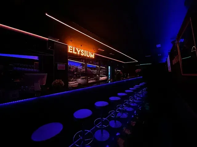 Un bar con un letrero de neón que dice Elysium.