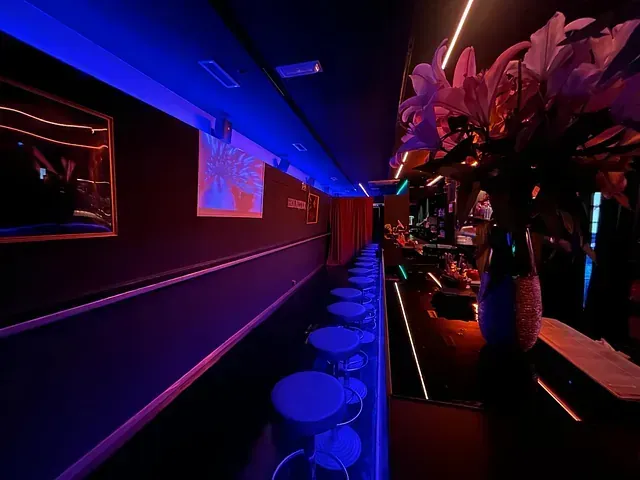 Una fila de mesas y sillas en una habitación oscura con luces azules.