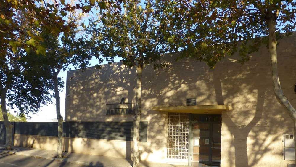 Un edificio con una valla y árboles delante.