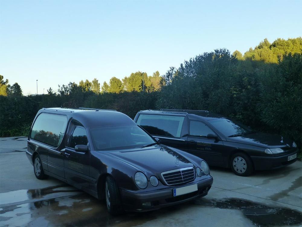 Dos coches negros están aparcados uno al lado del otro en un estacionamiento.