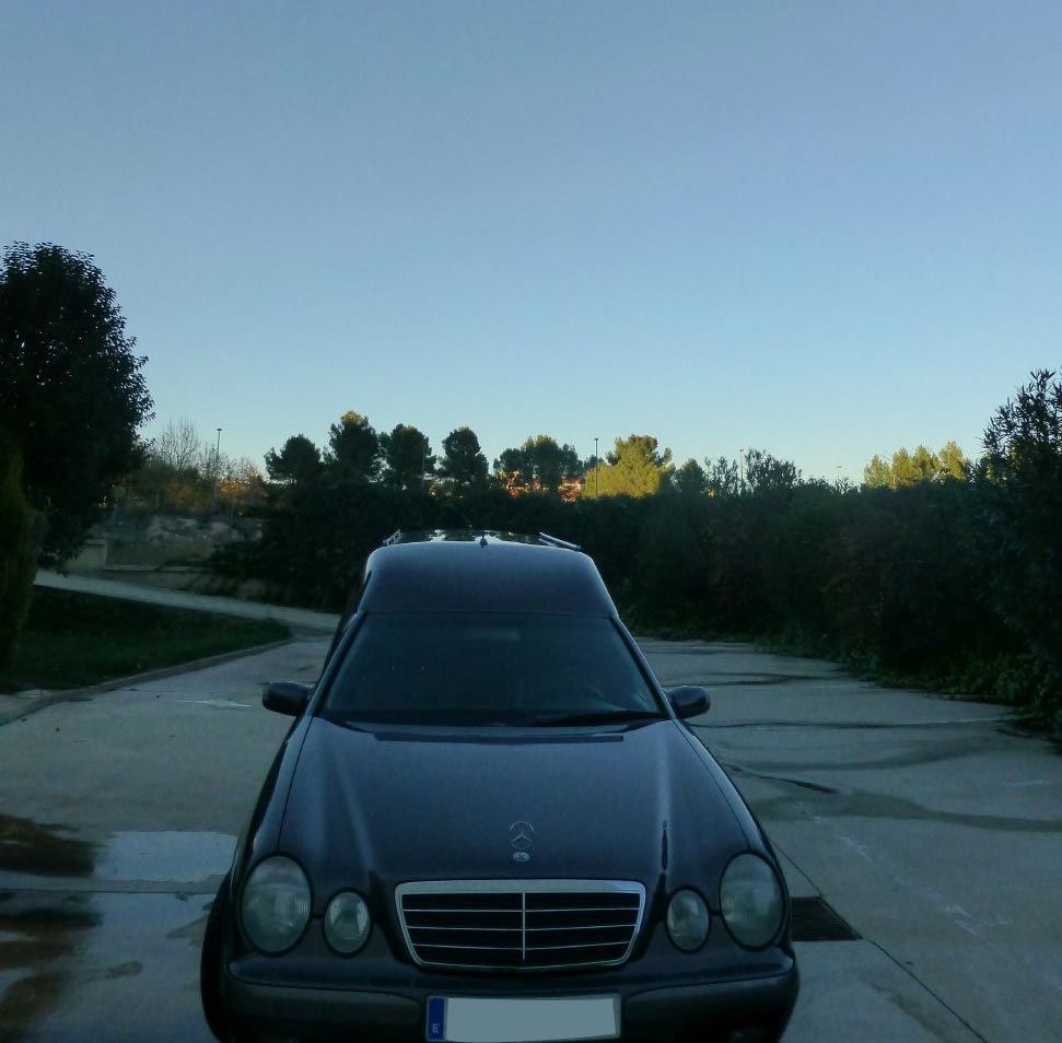 Un coche negro está aparcado al costado de la carretera.