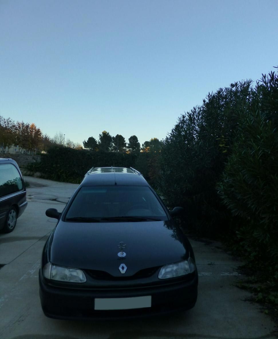 Un coche Renault negro está aparcado en un estacionamiento.