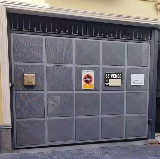 Un garaje vacío con la puerta del garaje abierta y un ventilador de techo.