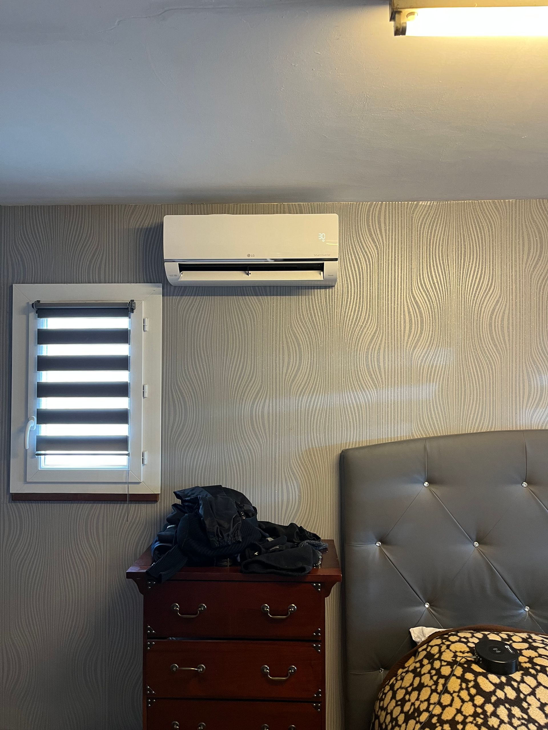 Mur de chambre avec fenêtre, climatiseur, commode et tête de lit