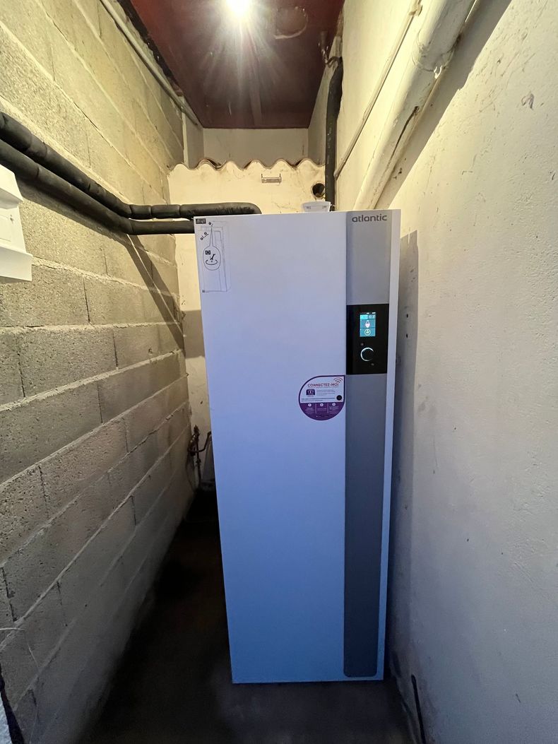 Distributeur automatique blanc dans un couloir étroit aux murs en parpaings et en plâtre.