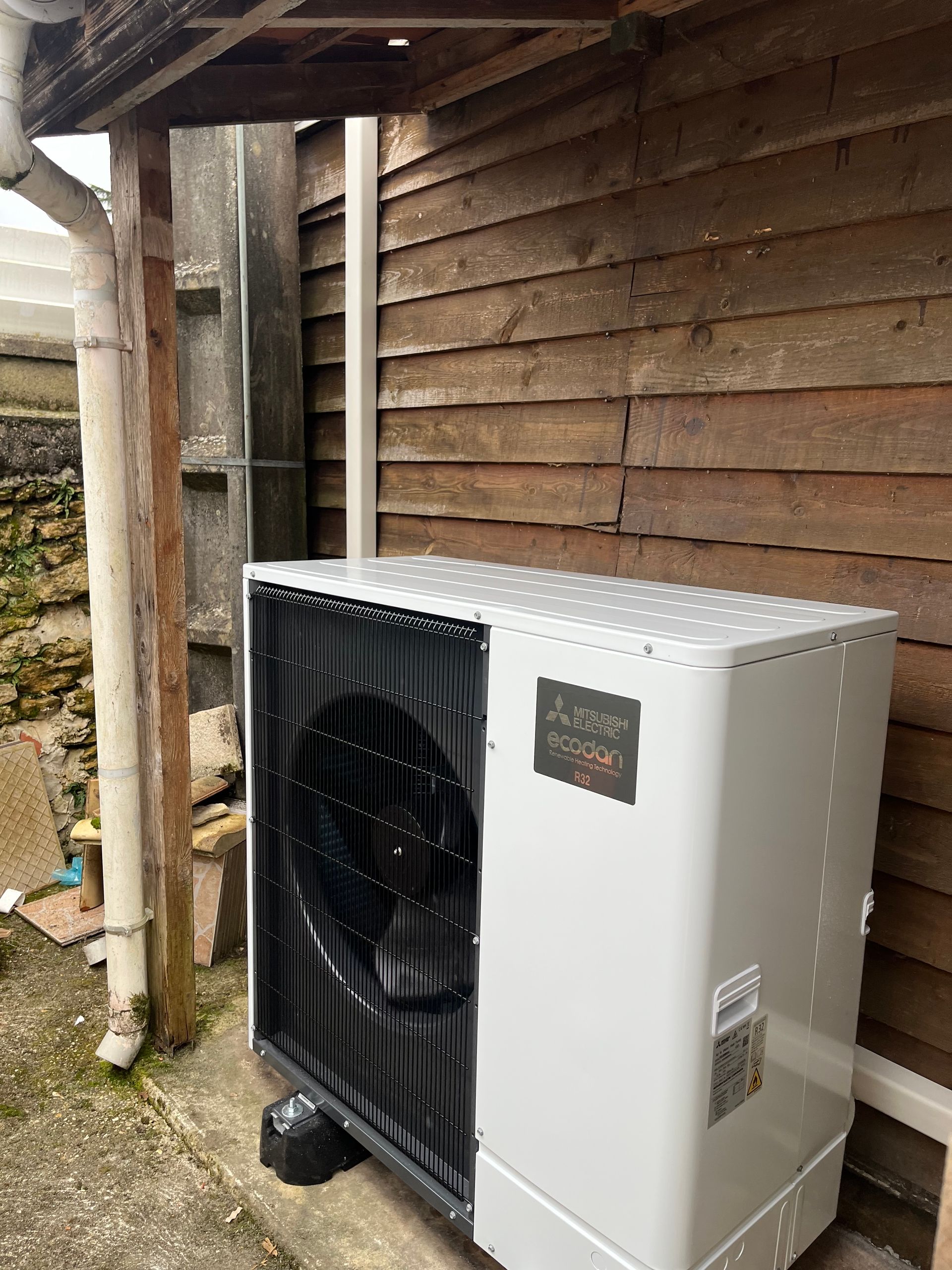 Unité de climatisation extérieure à côté d'un bâtiment en bois sous une zone couverte