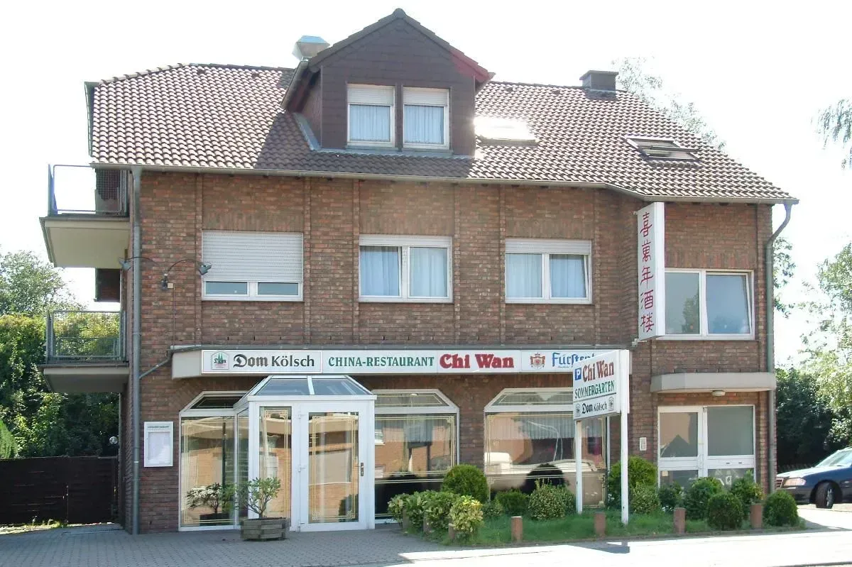 Dreistöckiges Backsteingebäude mit Ladenfront, weißer Markise und Ziegeldach, von der Straße aus gesehen.