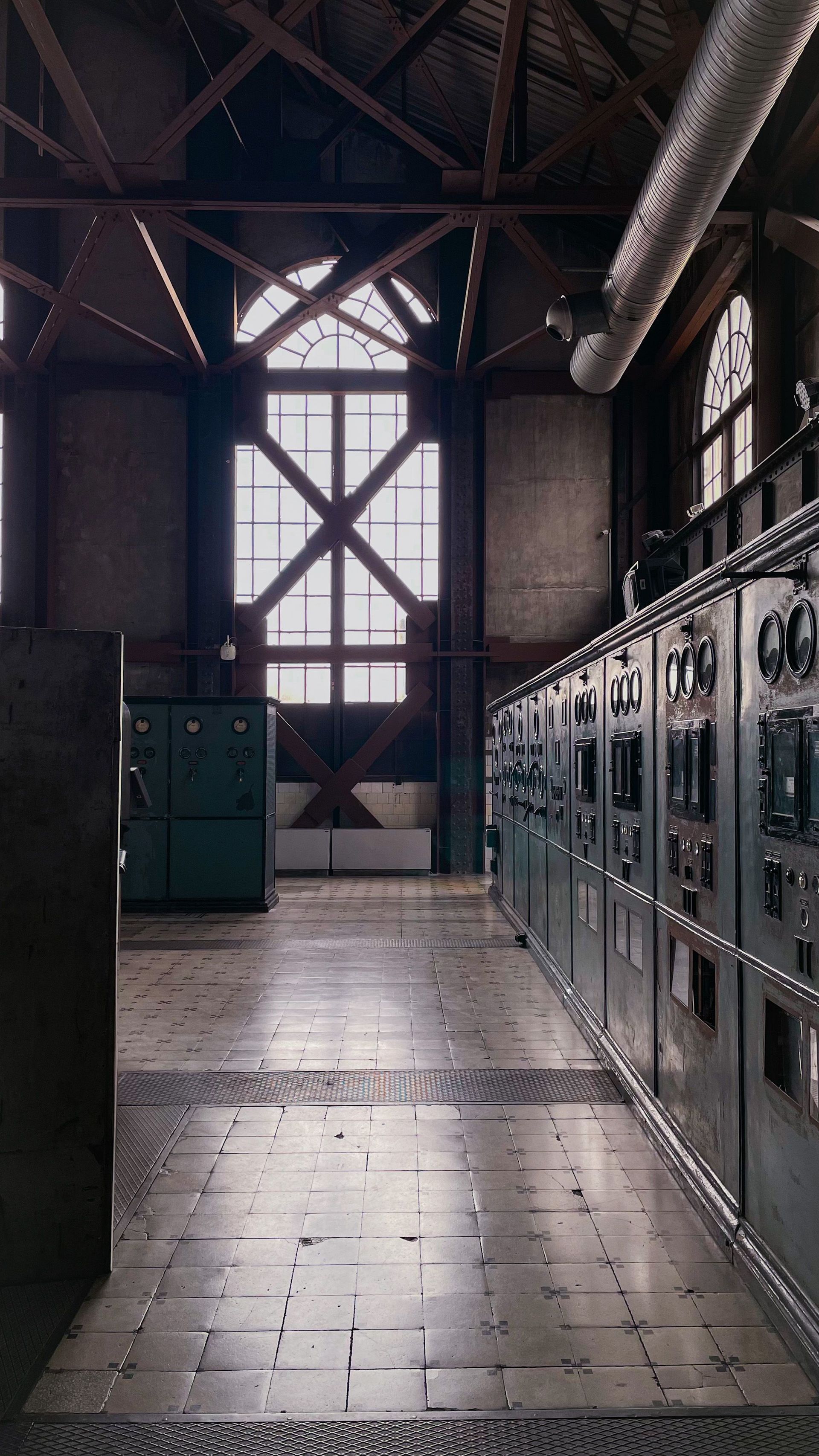Intérieur industriel avec casiers métalliques, parquet et haute fenêtre éclairant une pièce sombre