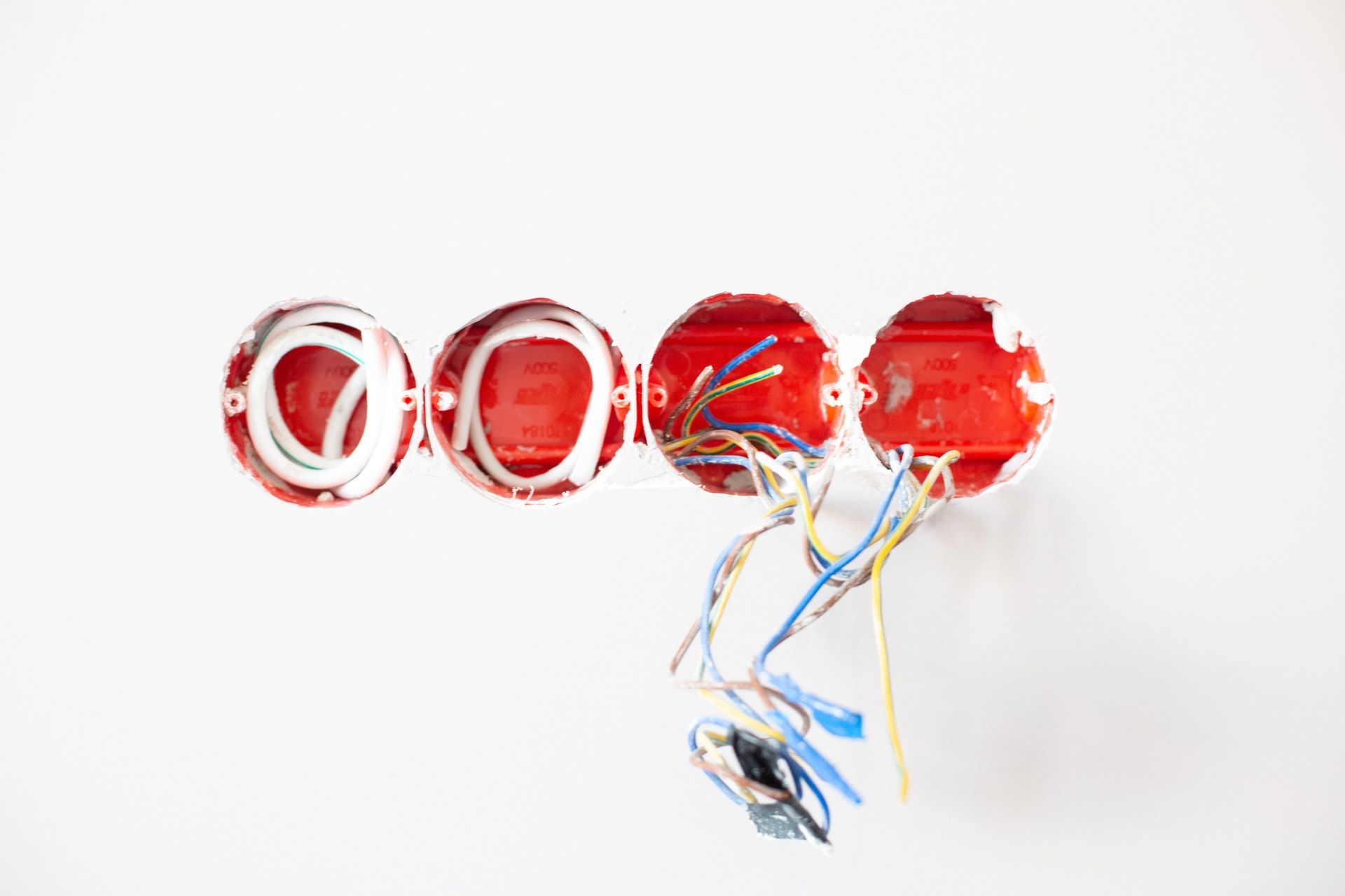 Quatre connecteurs de fils électriques rouges avec des fils multicolores sur fond blanc