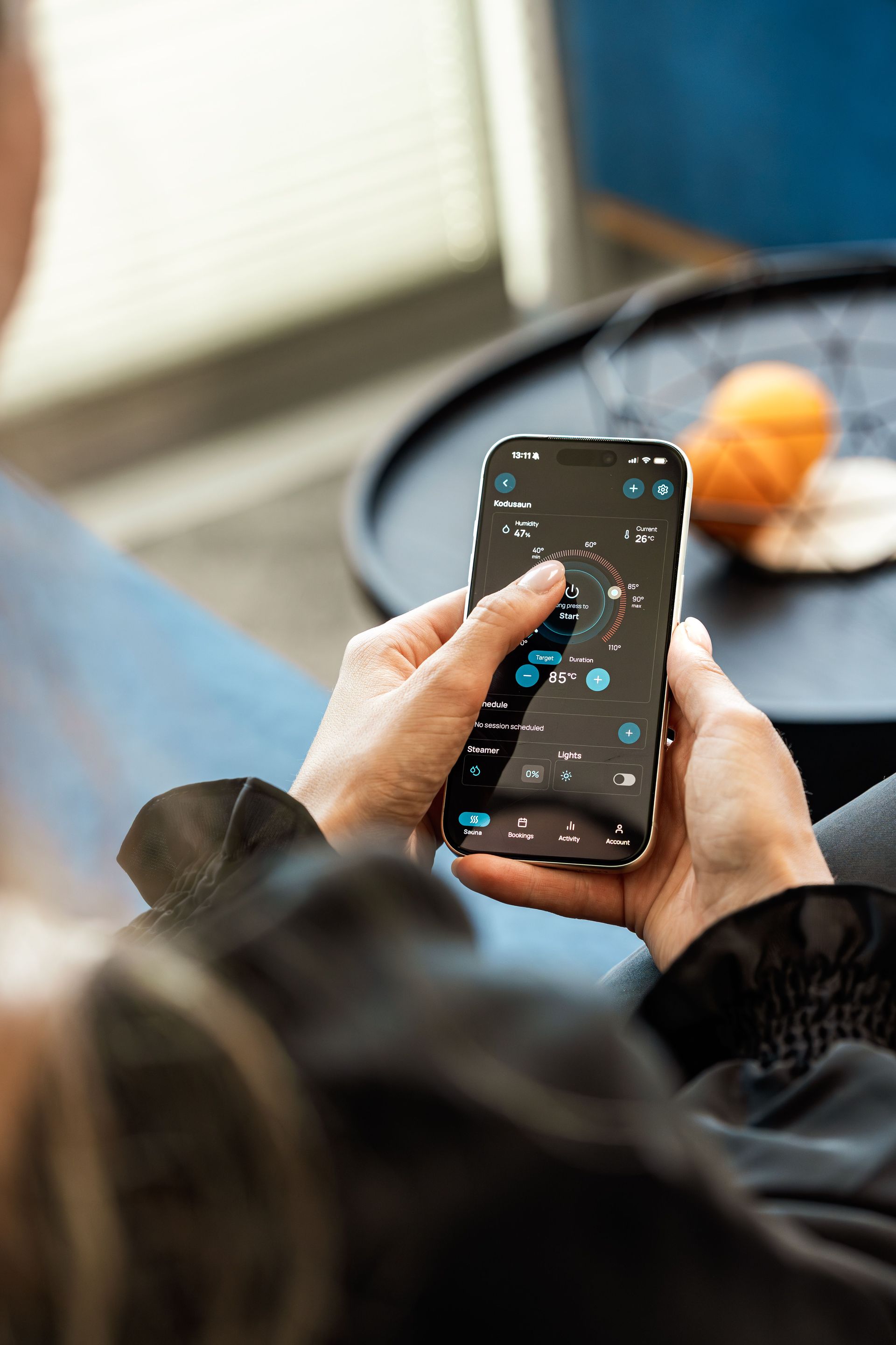 Une personne utilise un smartphone avec une interface d'application sombre, assise à une table avec de la nourriture en arrière-plan.
