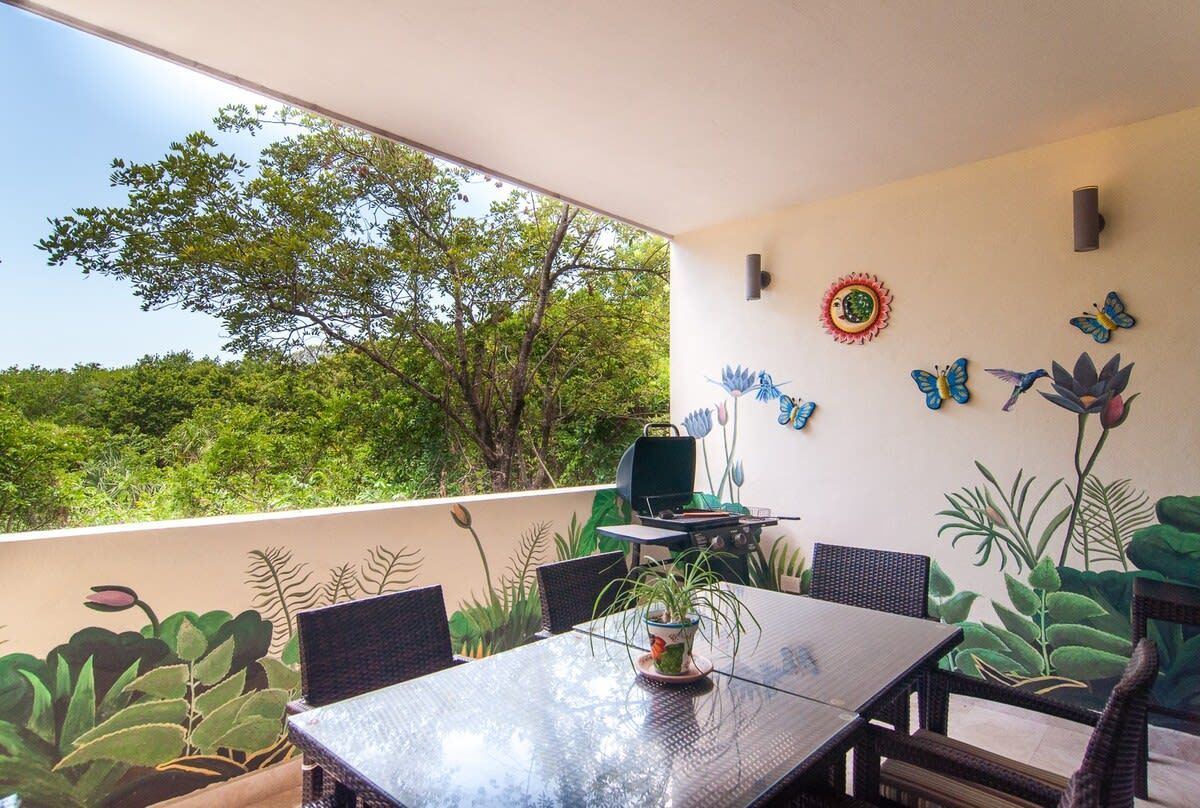 A table and chairs on a balcony with butterflies painted on the wall