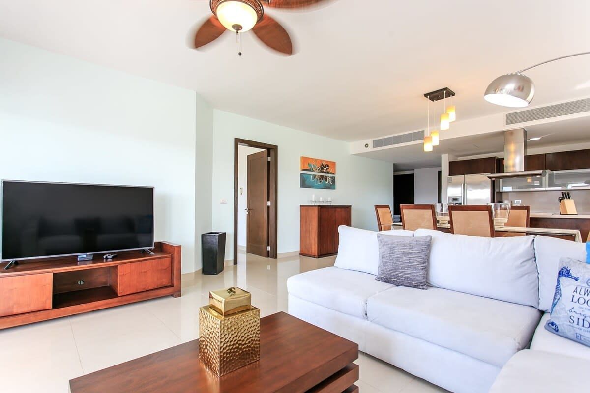 Una sala de estar con sofá , televisión , mesa ratona y ventilador de techo.