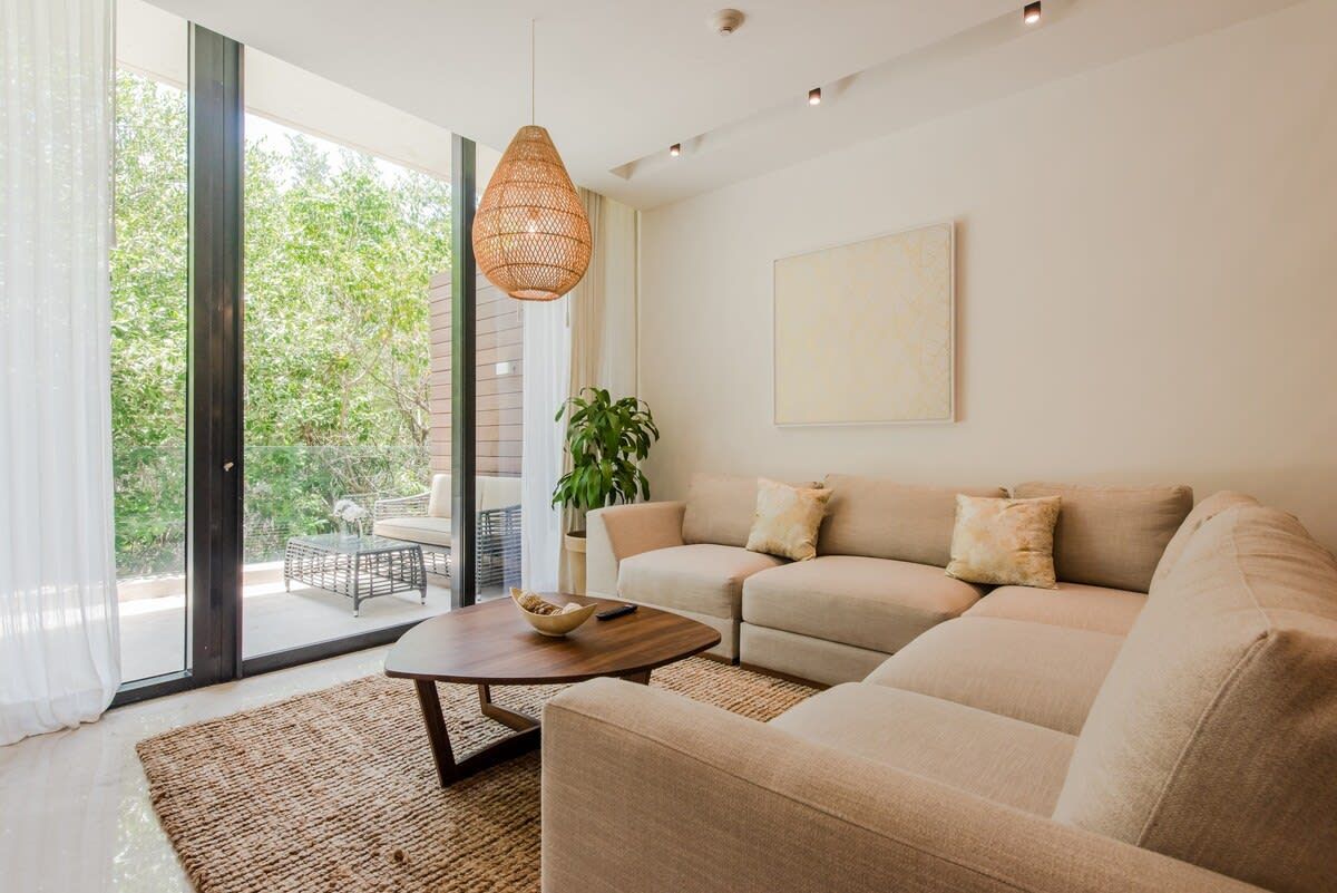 Una sala de estar con sofá , silla , mesa de café y grandes ventanales.