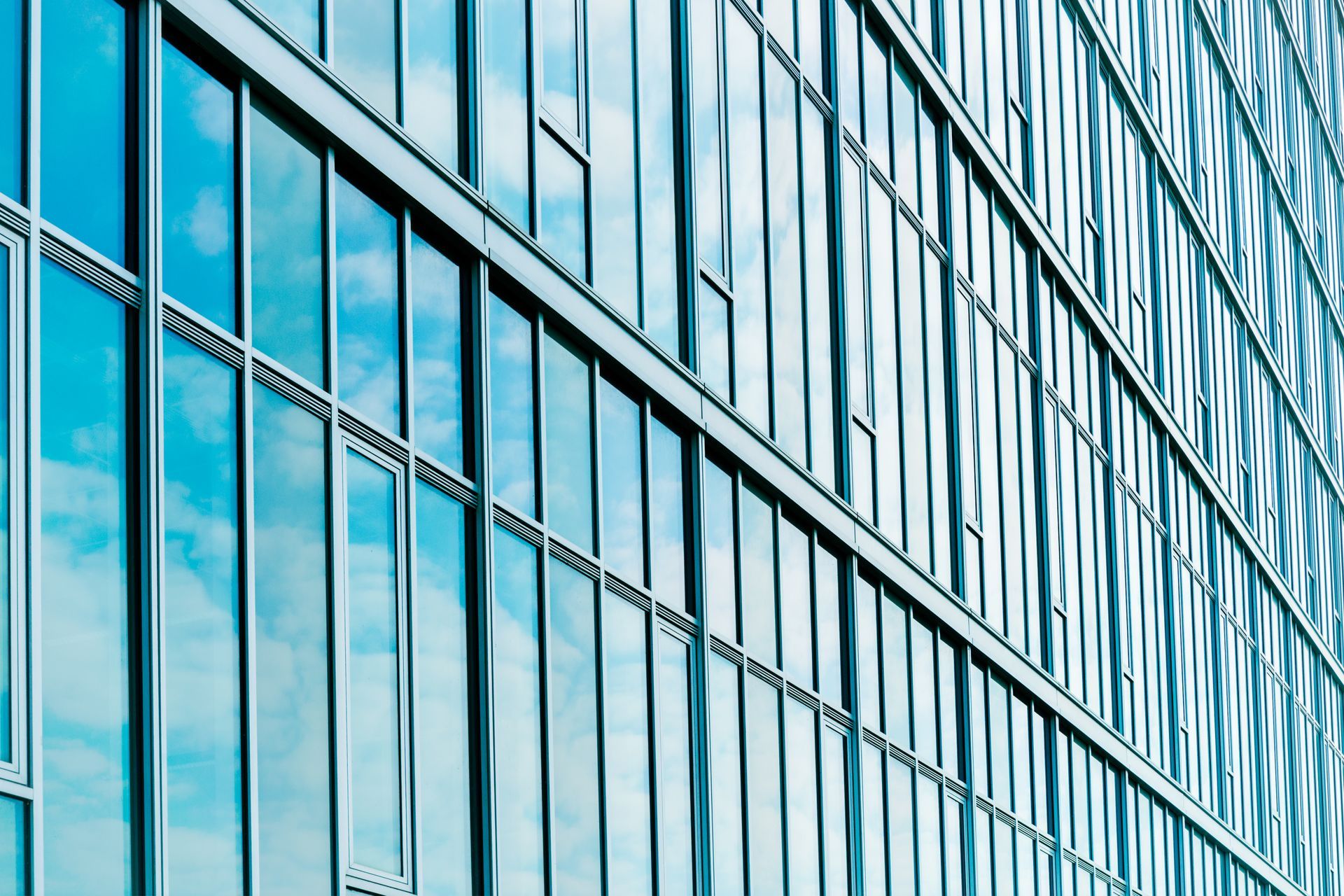Façade d’immeuble de bureaux en verre bleu, avec des fenêtres réfléchissantes et des lignes architecturales diagonales