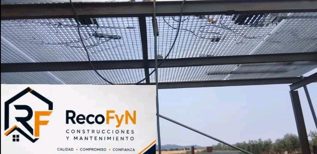 Logotipo de RecoFyN en un cartel blanco bajo una marquesina de malla negra contra el cielo.